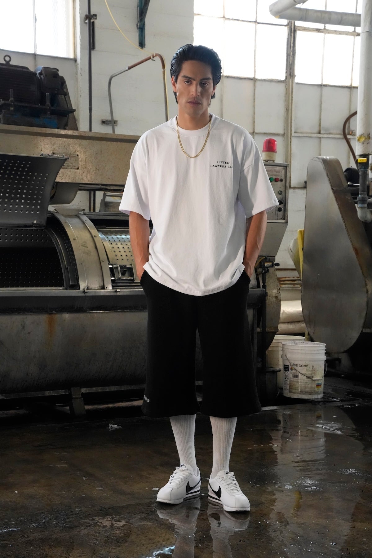 Model wearing a Heritage t-shirt and black Blvd. shorts standing in an industrial setting (White)