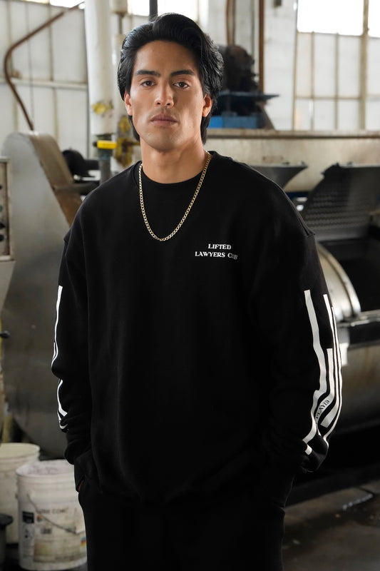 Person wearing the LLC Chrome black sweatshirt with logo LIFTED LAWYERS CLUB and stripes in an industrial setting