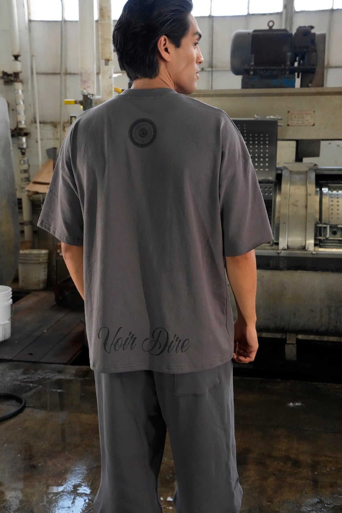 Model wearing a Heritage 'Voir Dire' t-shirt and Blvd. shorts in an industrial setting (Gray)