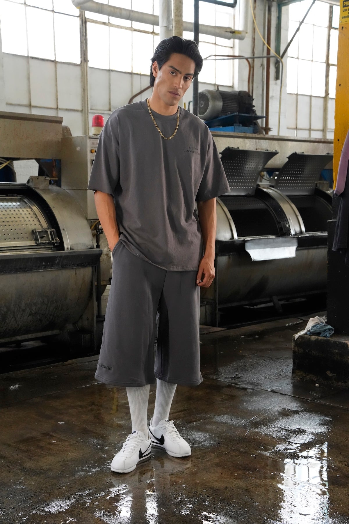 Model Man wearing a Heritage t-shirt with Blvd. shorts standing in an industrial setting with Nike Cortez sneakers (Gray)